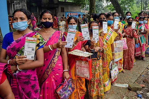 Women standing in line holding up their Aadhaar, the government's move towards Aadhaar-voter ID linking has faced major criticism