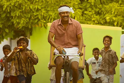 Samuthikarini in a veshti riding a cycle with kids in the background