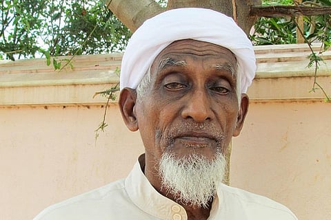 Ali Manikfan with grey beard wearing a white headcover and white shirt