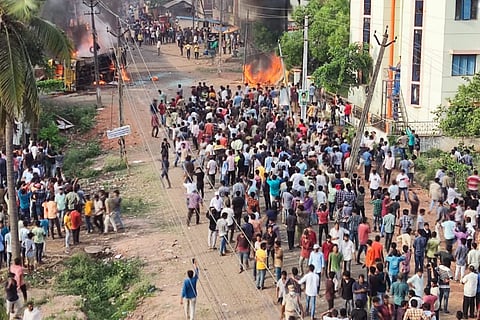 A mob gathered on road while a bus is on flames