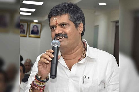 Andhra Pradesh Tourism Minister Avanthi Srinivasa Rao wearing a white shirt and speaking in a mic