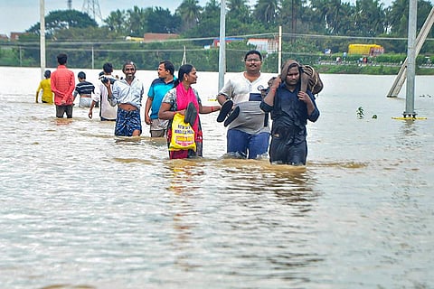 People carrying their belongings through an inundated street amid the Andhra floods