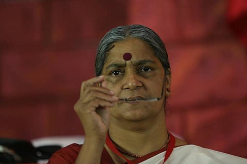 Annie Raja wearing a big red Bindi and holding her spectacles