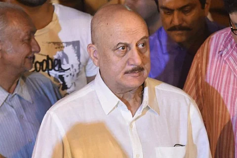 Anupam Kher is seen wearing a white shirt in the image.
