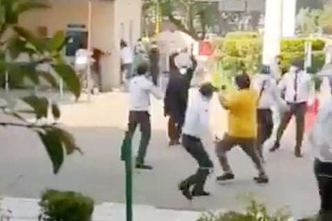 A man is seen hitting a few men with a stick as others try to run away.