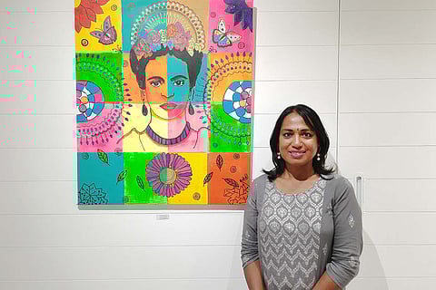 Kalki Subramaniam standing with a portrait of Frida Kahlo