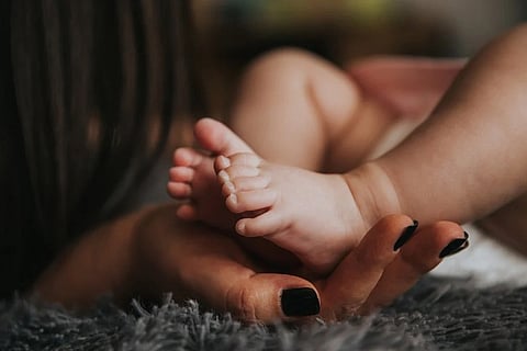 A baby's legs kept on the hands of a woman