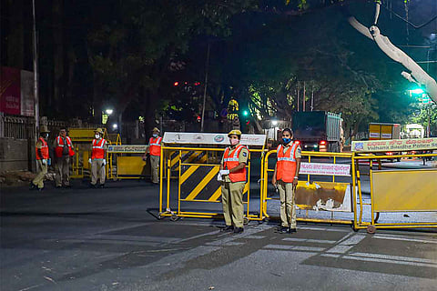 Bengaluru police standing on the road with barricades