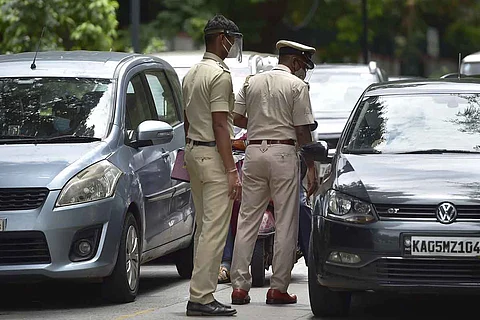 Two policemen walking on a street amid traffic