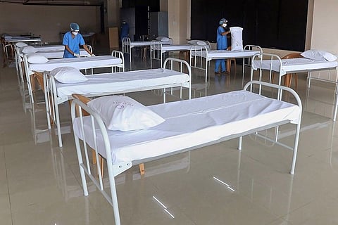 Two staff prepping beds for COVID-19 patients at a centre in Bengaluru