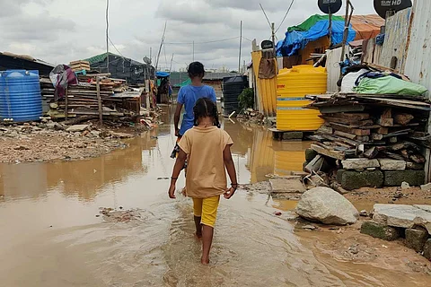 A small child and a person walking in flooded area