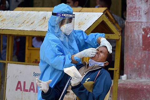 A health worker in a PPE suit collecting nasal swab sample from a woman for coronavirus test