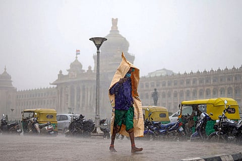 Man walking in the rain in front of Vidhana Soudha