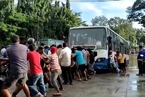 Bengaluru residents pulling a bus out of a flooded road