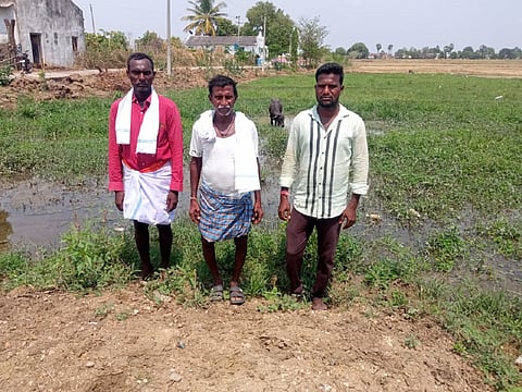 Three men standing in front of a field