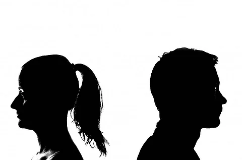 A man and a woman stand back to back in black and white image
