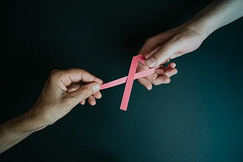 Women holding a pink ribbon for breast cancer