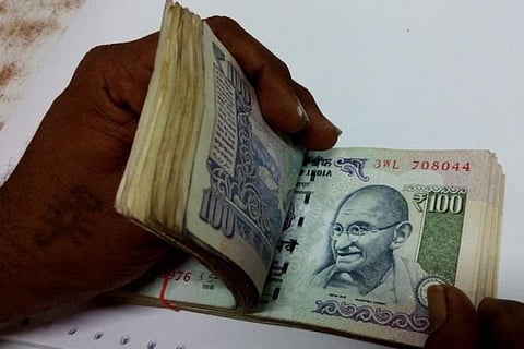 Person counting a bundle of Rs 100 notes