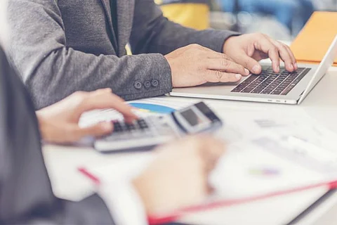 People in a work station with laptops and calculator