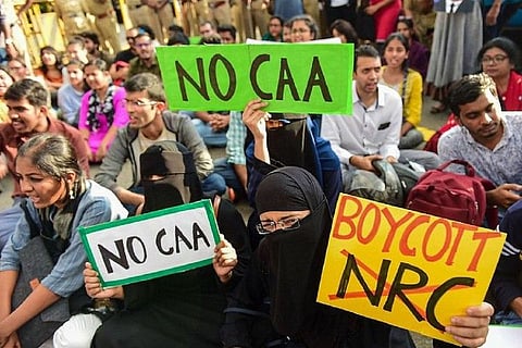 People at a protest holding up anti-CAA banners