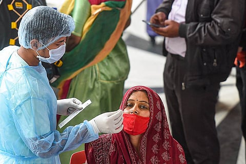 A health worker collects swab sample of an outstation passenger for COVID-19 test