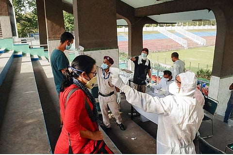 A health worker screening a woman for coronavirus