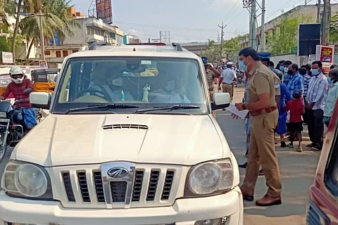 A Chennai police official talking to the passengers in the vehicle as passers-by are looking on.