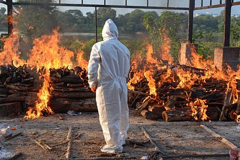 A PPE suit worn official taking care of a tradiational cremation site