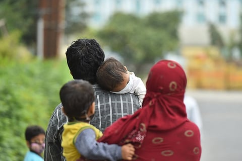 Carrying young children a couple covered with facemasks walking on a road