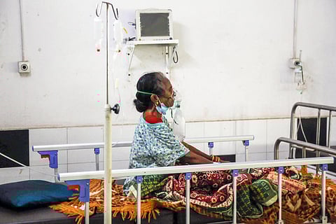 A woman sitting up and breathing oxygen through a mask in a hospital