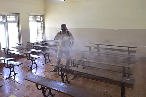 A health worker sprays disinfectant inside a classroom