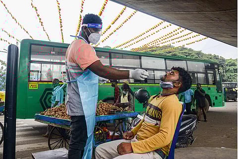 A medic collects swab sample of a commuter for Covid-19 test, in Bengaluru
