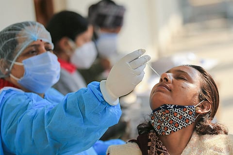 A health worker collecting samples from a woman for a COVID-19 test