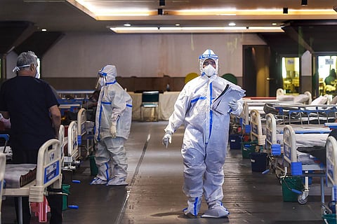Medical professional in a white PPE kit standing in the middle of a COVID-19 ward