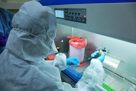 A health worker wearing protective gear testing a sample at a lab
