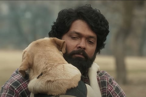 Screengrab from 777 Charlie showing Rakshit Shetty hugging the dog