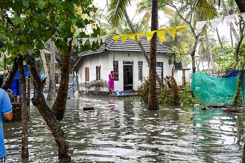 Woman standing in front of flooded house in Chellanam