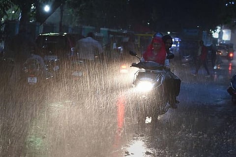 A woman rides a bike in heavy rain