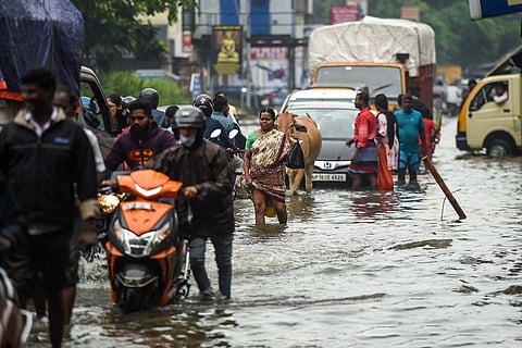People wade through a flooded street in Chennai after heavy rains