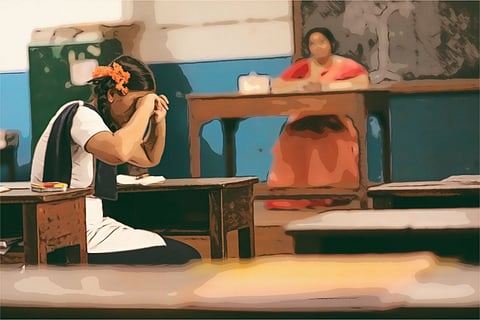 School girl crying in classroom as teacher looks on