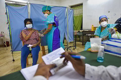 Vaccination drive underway in Chennai with a woman getting a shot by a nurse as a man fills in a card in the foreground