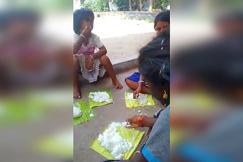 Children eating food from a small leaf