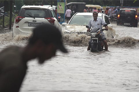 Commuters wade through a waterlogged road after heavy rains
