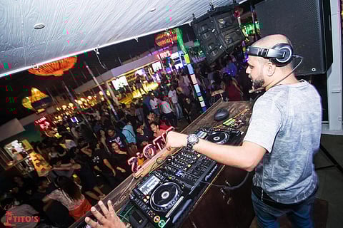A DJ next to his console at Club Titos as the crowd before him dances away
