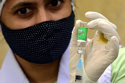 A woman holding up Serum Institute of India's Covishield Vaccine