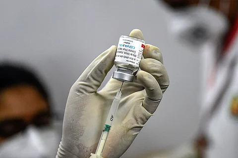 A health worker holding up a small bottle containing Covaxin COVID-19 vaccine