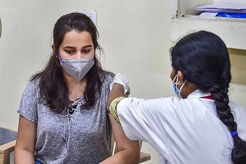 A health worker vaccinating a woman