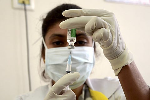 A medical worker prepares to administer Covishield dose