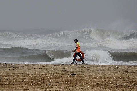 A lifeguard walks along the sea shore as waves crash onto the shore ahead of the landfall of cyclonic storm Mandous