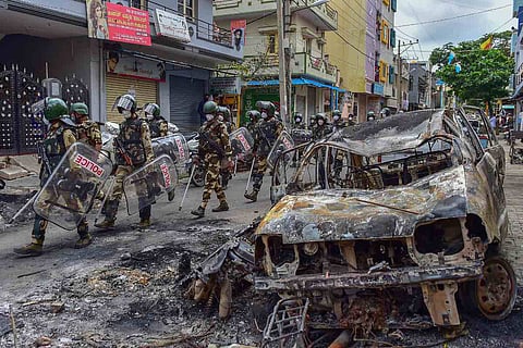 Security personnel carry out a flag march in the riot-hit area after a mob went on a rampage on Tuesday over a social media post